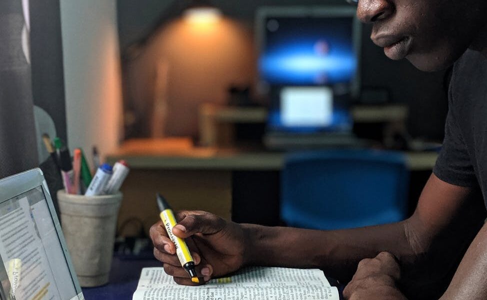 Man deeply engaged in studying with a book and tablet at a desk