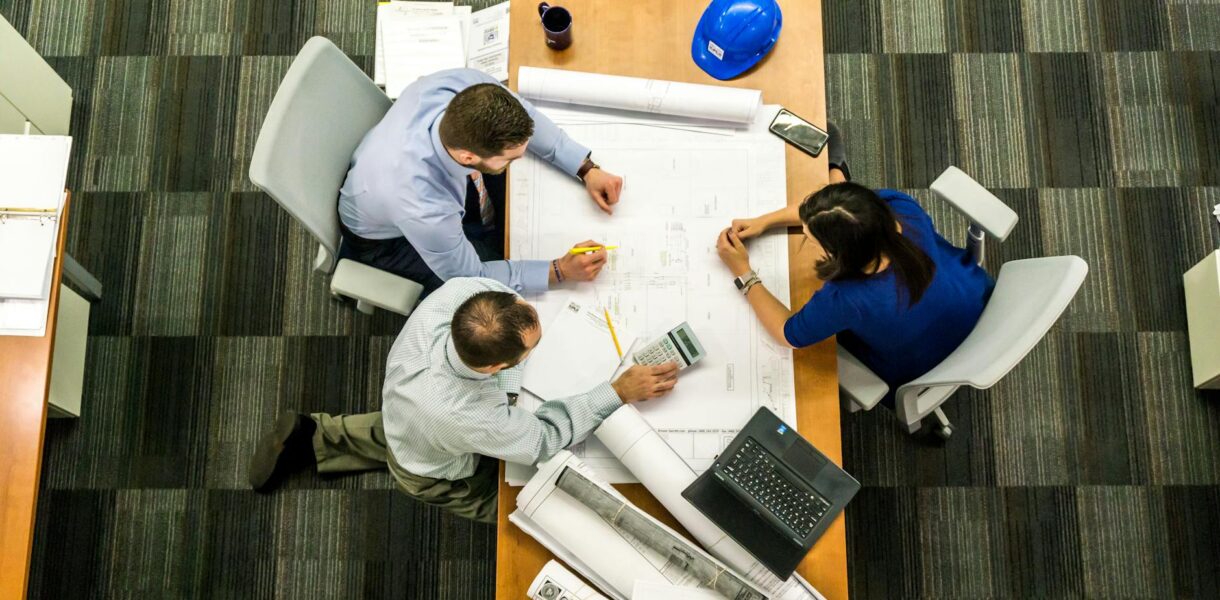 Top view of a team working on construction plans in an office setting.