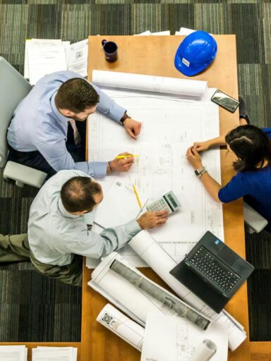 Top view of a team working on construction plans in an office setting.